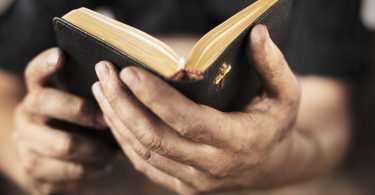 Dirty hands holding an old bible. Very short depth-of-field